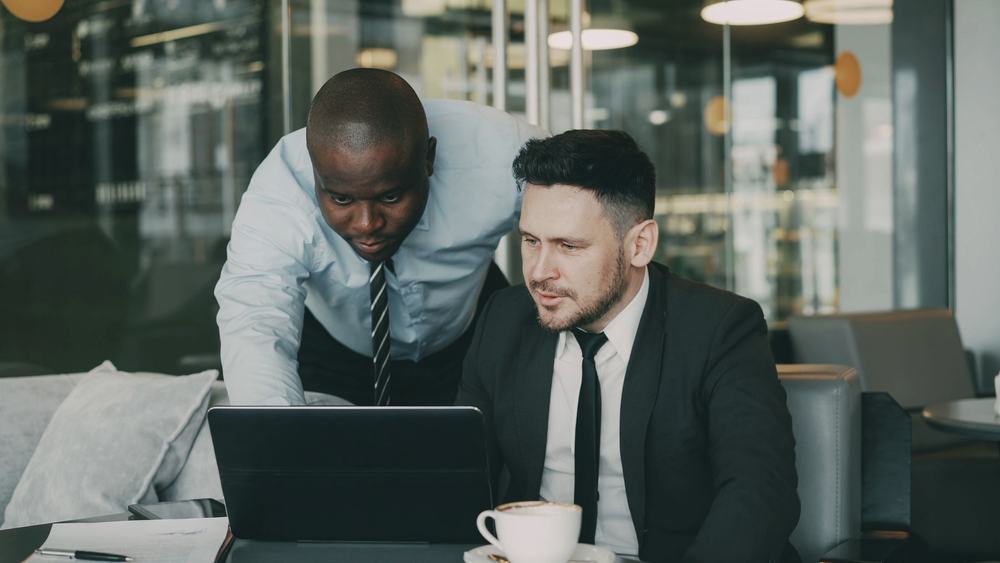 Two colleagues reviewing property figures on a laptop in an office.