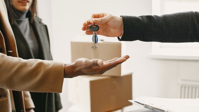 A set of keys being handed from one person to another over an open palm.